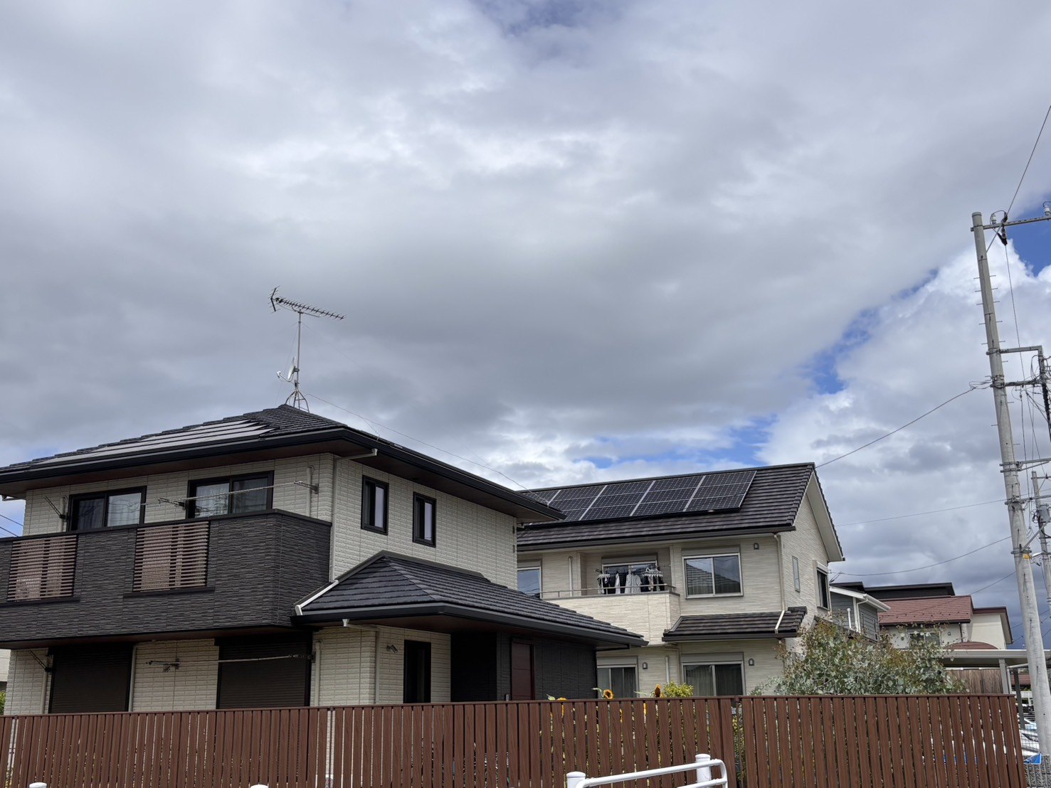 塀越しに見える2棟の戸建てと太陽光パネル